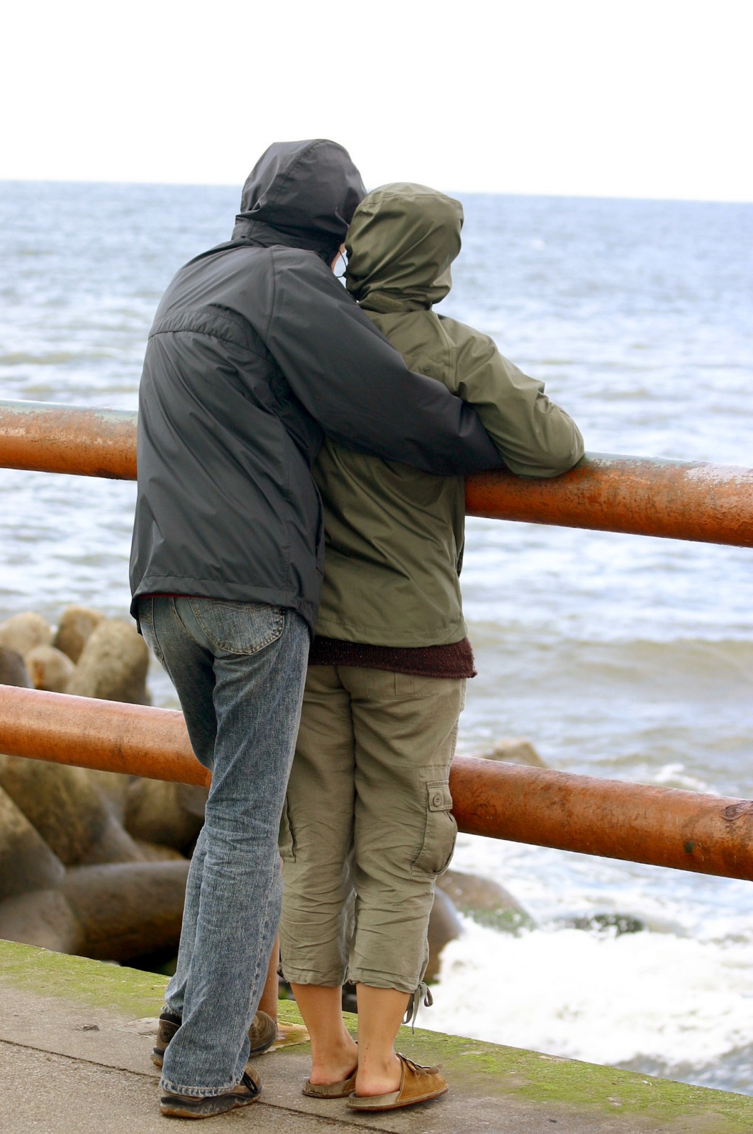 Man omhelst vrouw op de dijk terwijl ze samen naar de zee kijken en nadenken over abortus